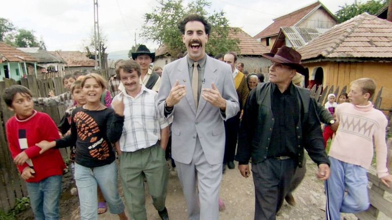 Borat in Kazakhstan, walking alongside several citizens, smiling. A scene from Borat! Cultural Learnings of America Make Benefit Glorious Nation of Kazakhstan.