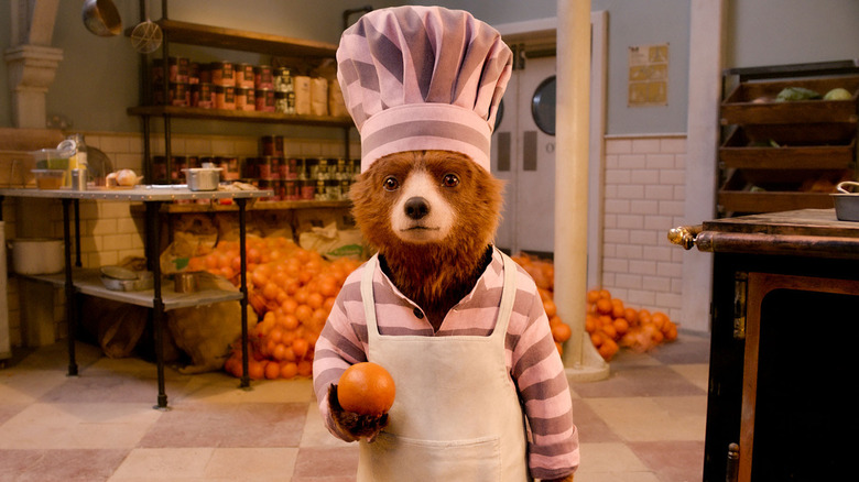 Paddington Bear holds an orange in his pink prison stripes