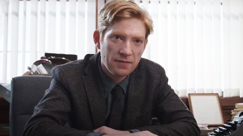 Domhnall Gleeson's Ned Sampson smiles as he sits at his desk in The Paper