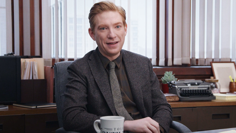 Domnhall Gleeson as Ned Sampson sits at his desk in The Paper