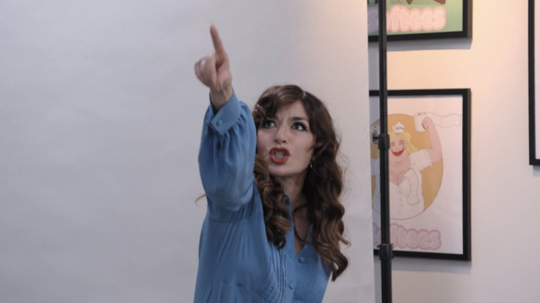 Sabrina Impacciatore as Esmeralda Grand points upwards during an audition in The Paper
