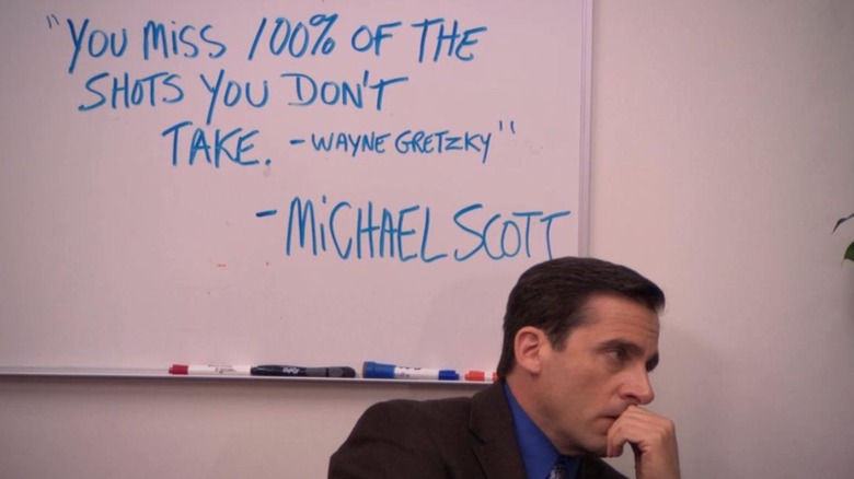Michael Scott sat in front of a board that has famous Wayne Gretzky quote written on it