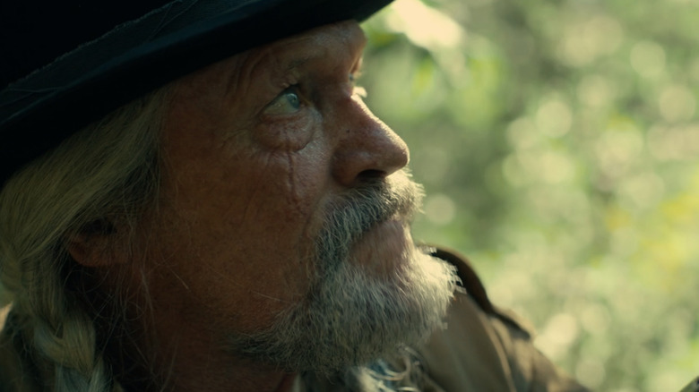 Michael Rooker as Red St. Wild looking upward in the forest in Peacemaker season 2
