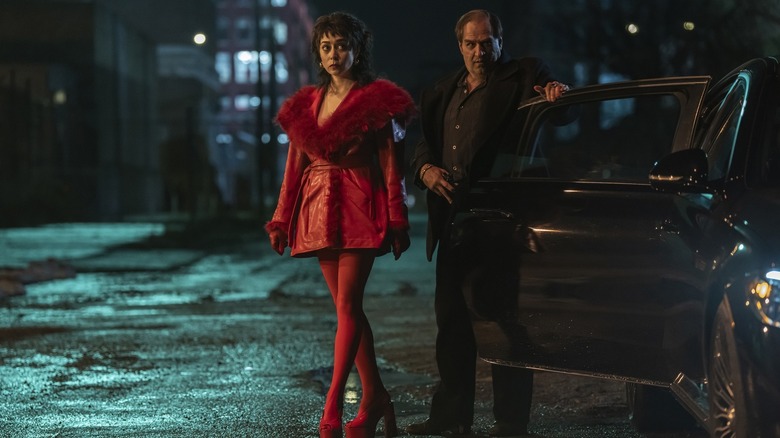 Cristin Milioti as Sofia Gigante in a red outfit walking next to Colin Farrell as Oz Cobb getting out of a car in The Penguin