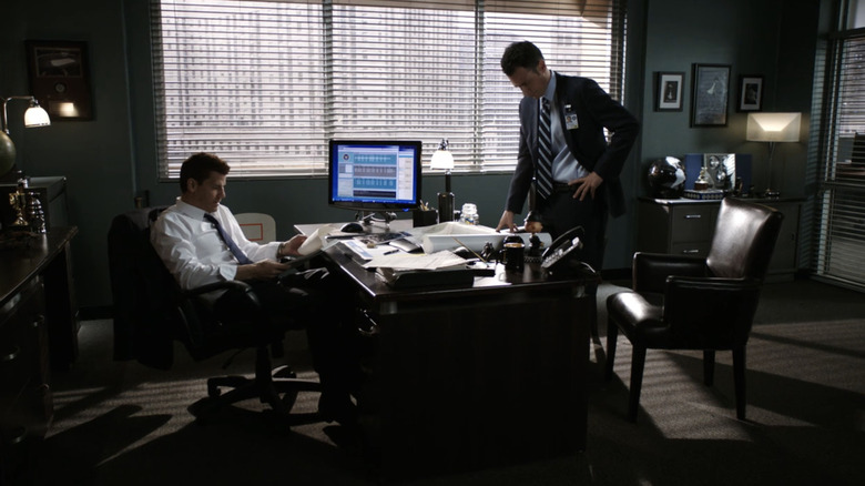 Bath David Burinaz Selly sits behind his office alongside a man wearing a bone suit