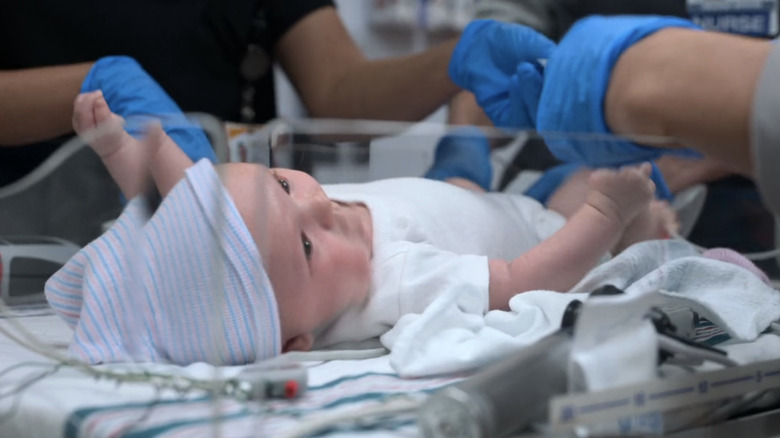 A baby is shown laying in a  hospital crib in The Pitt