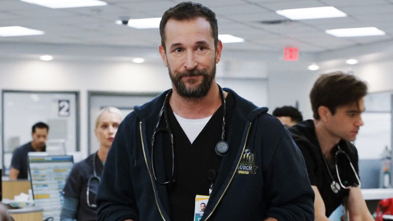 Noah Wyle's  Dr. Michael Robinavitch stands in the ER with hsi staff working in the background in The Pitt