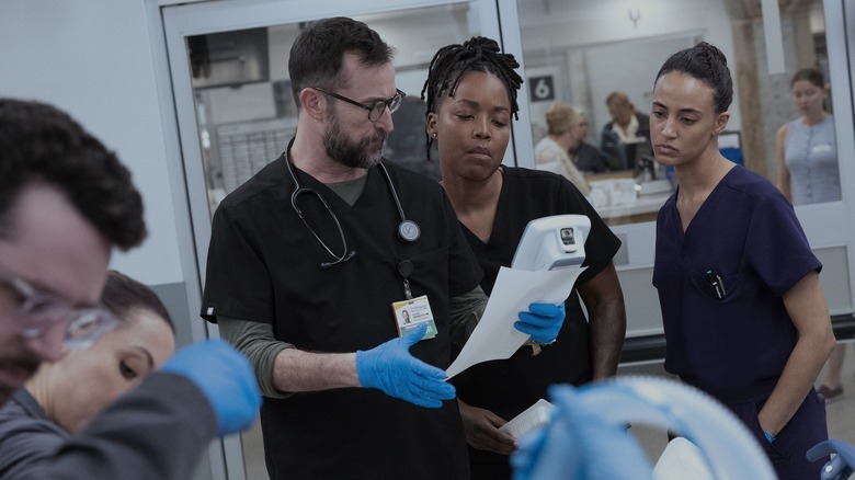 Robby, Ellis, and Garcia look at a readout during a surgical procedure in The Pitt