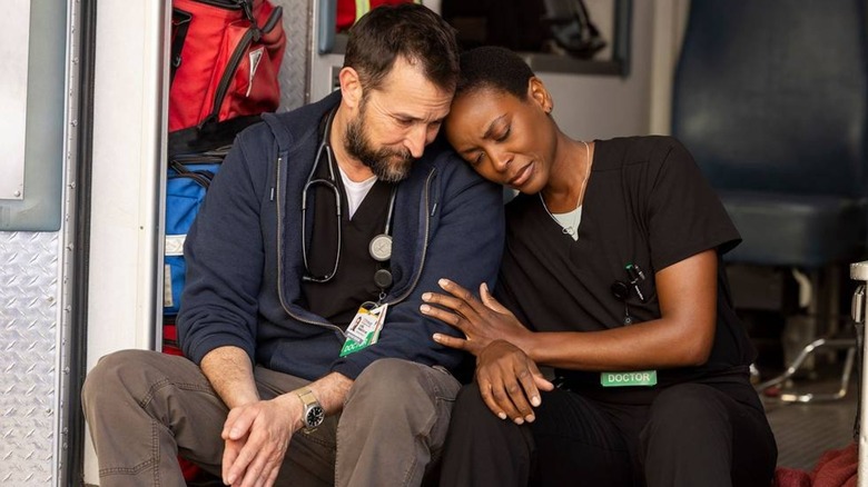 Noah Wyle's Dr Michael Robinavitch sits next to Tracy Ifeachor's Dr Heather Collins in the back of an ambulance in The Pitt.jpg
