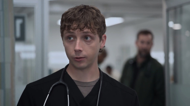 Gerran Howell's Dennis Whitaker looks across frame as Noah Wyle's Dr Michael Robinavitch watches from the door behind him in The Pitt
