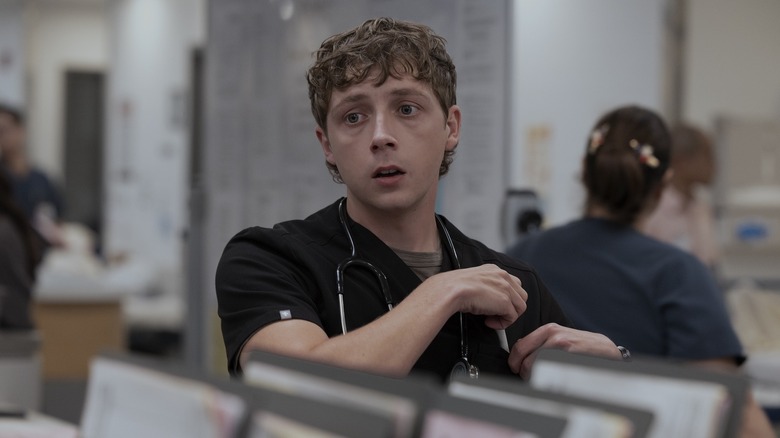 Whitaker tucks a pen into his pocket in The Pitt