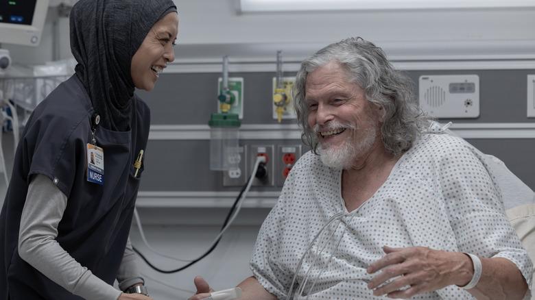 Amielynn Abellera as Perlah and Jeff Kober as Duke laughing together in The Pitt
