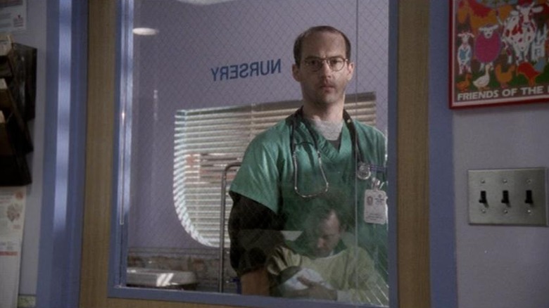 தி பிட்டில் உள்ள நர்சரி ஜன்னல் வழியாக தனது குழந்தையை வைத்திருக்கும் சீனை மார்க் பார்க்கிறார்