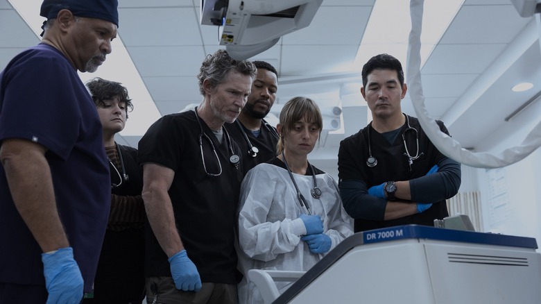A bunch of doctors stand around a patient on an operating table in The Pitt