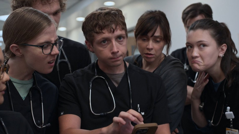 Dr. King, Dr. Whitaker, Dr. McKay, and Dr. Santos reacting to an image on Whitaker's phone in The Pitt