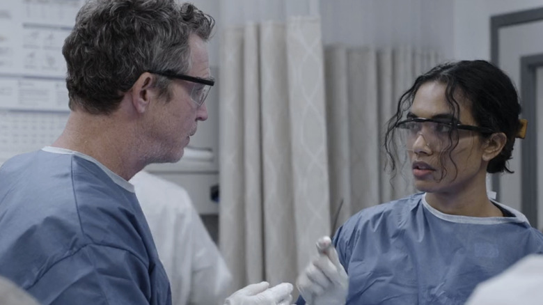 Supriya Ganesh as Dr. Mohan looks at Sean Hatosy as Dr. Abott in a surgery room in The Pitt