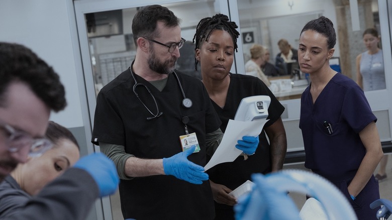 Dr. Robby reading a piece of paper while Drs. Garcia and Ellis look on in The Pitt season 2