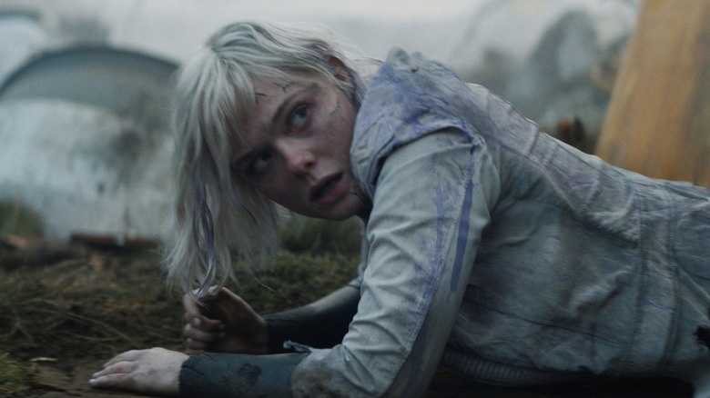 Elle Fanning as Thia crawling on the ground and covered in dirt in Predator: Badlands