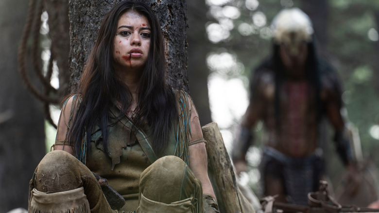 Amber Midthunder while Naru is hiding behind a tree from Yautja (Dane Diliegro) in prey