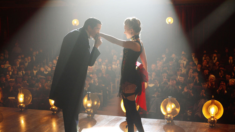 Christian Bale kisses Scarlett Johansson's hand on stage in front of an audience