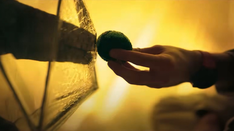 Ryan Gosling as teacher/astronaut Ryland Grace extending an orb shaped like Earth to an alien claw in Project Hail Mary