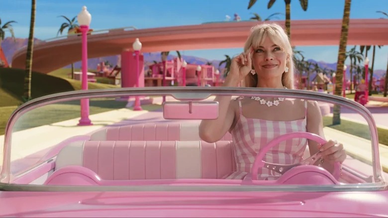Barbie driving a pink car and saluting
