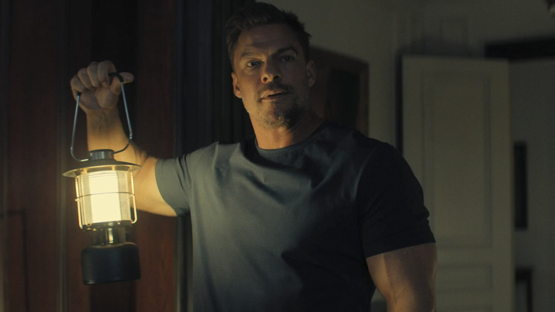 Reacher holding an oil lamp in Reacher season 3