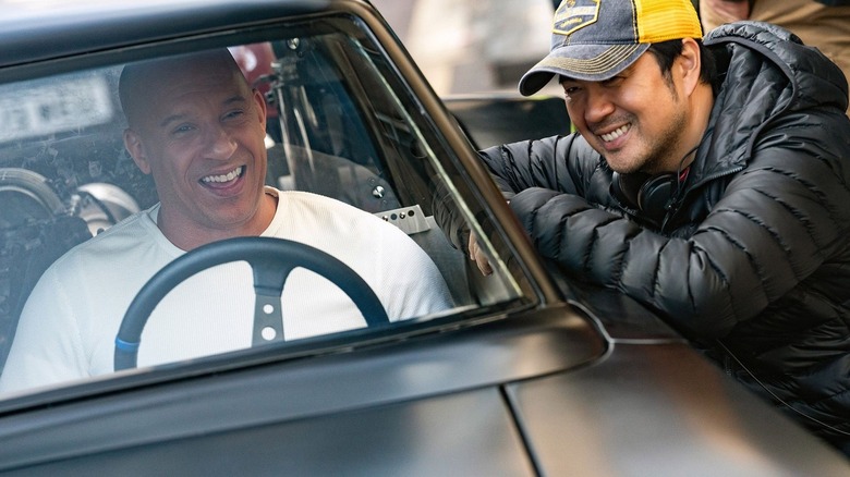 Director Justin Lin smiling with Vin Diesel as Dominic Toretto in a car in Fast 9