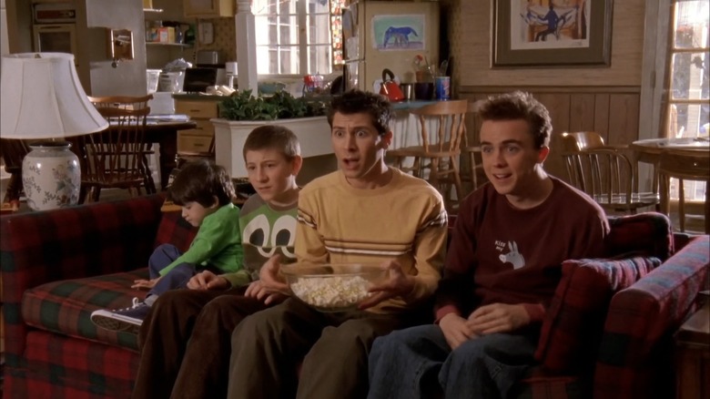 Brothers Jamie, Dewey, Reese and Malcolm sit on the couch watching tv in a mix of awe and horror in 