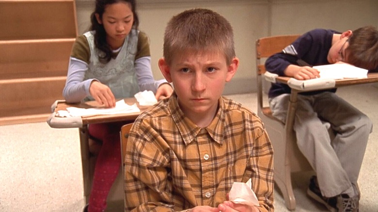 Dewey sulks in a dingy classroom surrounded by bored students in 