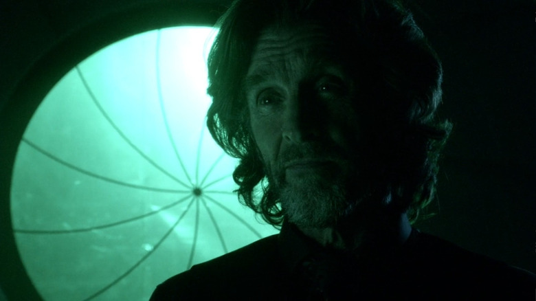 John Glover as Lionel Luthor standing in front of green light in Smallville