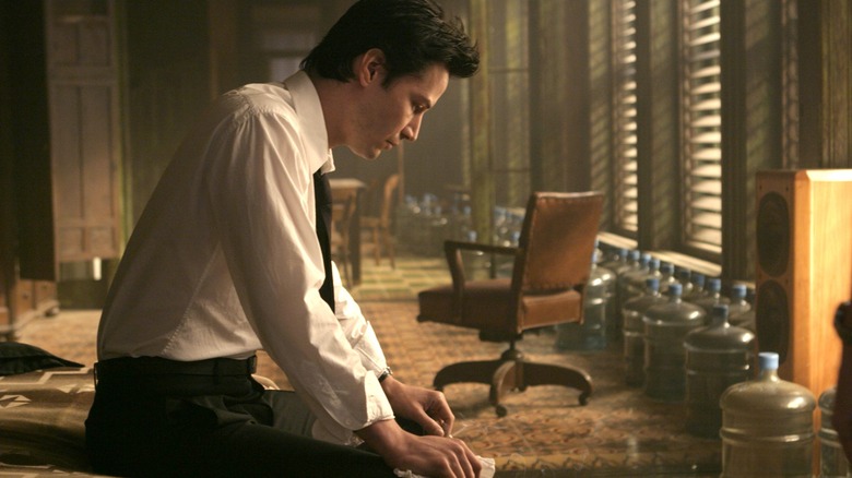 John Constantine sits on a bed that looks sad in Constantine.