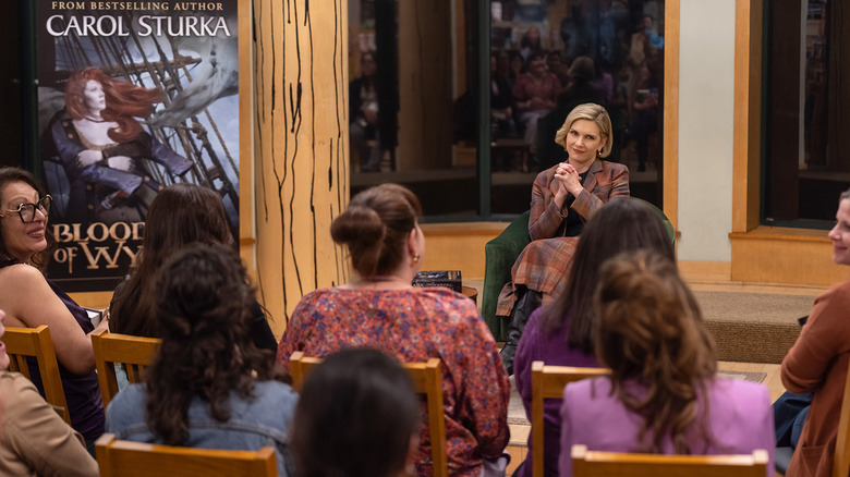 Carol Sturka van Rhea Seehorn verzorgt een live lezing van haar boek in Pluribus