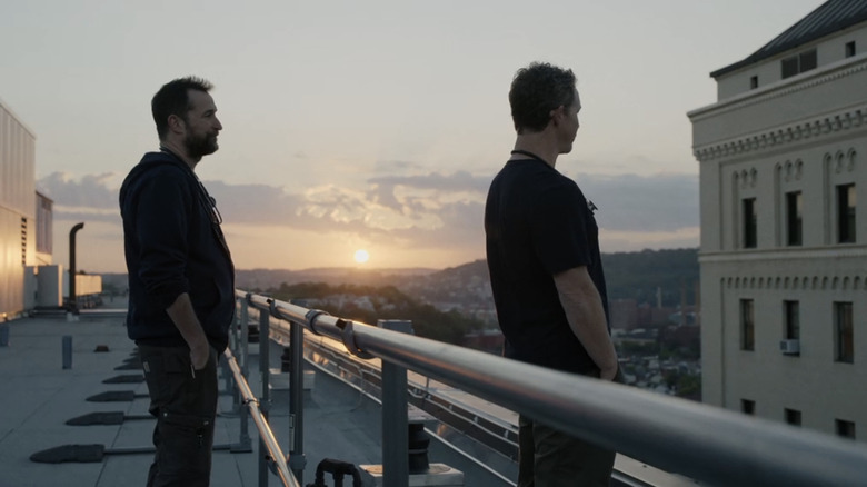 Noah Wyle's Dr Michael Robinavitch stands behind Sean Hatosy's Dr Jack Abbot on the roof of a hospital in The Pitt