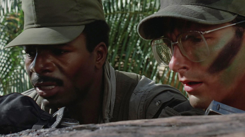 Carl Weathers as Dillon and Shane Black as Hawkins crouched behind a log in Predator