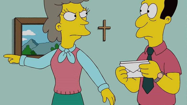 Helen Lovejoy, angry at her husbandm the reverend, as she points at something off-screen. A cross is on the wall. The reverend holds letters.