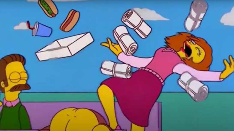 Maude Flanders getting hit with a barrage of flying t-shirts, her stadium snacks fly everywhere.