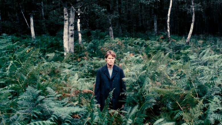 Willem Dafoe's character standing in a forest in Antichrist