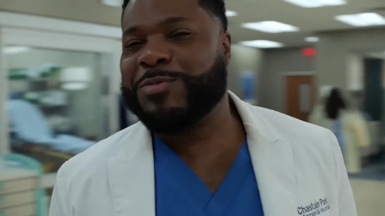 Jamal-Warner's AJ Malcolm smiles as the hospital lobby blurs with traffic behind him in the residency