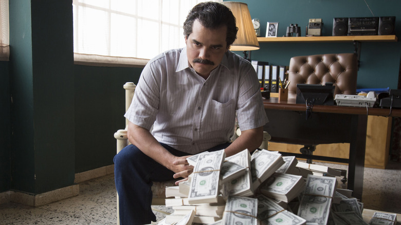 Wagner Moura as Pablo Escobar sitting by a pile of money in Narcos
