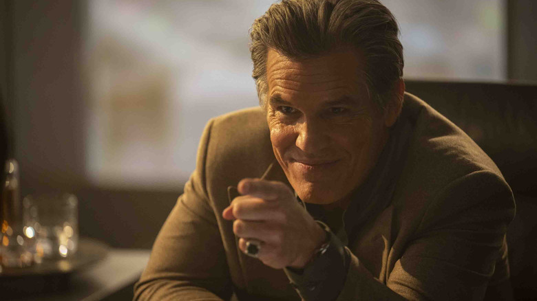Josh Brolin as Dan Killian sitting at his desk looking smug in The Running Man