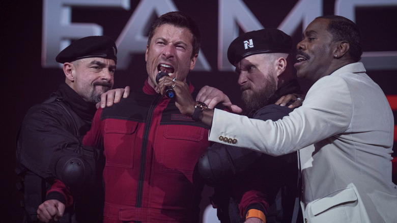 Ben Richards (Glen Powell) shouts into a microphone held by Bobby T (Colman Domingo) in The Running Man (2025)