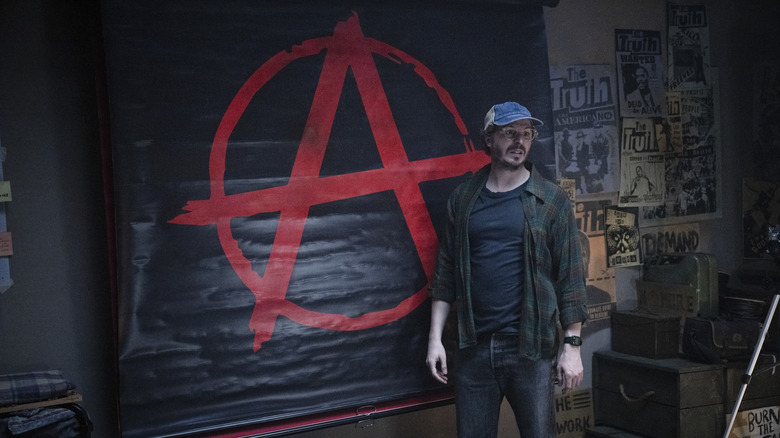 Elton Parrakis in front of an anarchy symbol in The Running Man