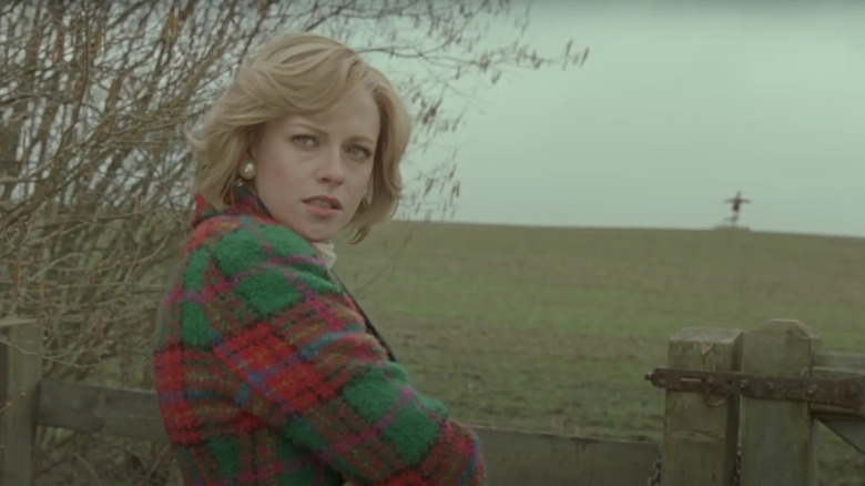 woman in red and green plaid coat looking worried over her right shoulder outside