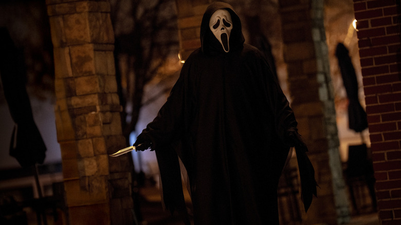 Ghostface brandishing a knife outside a house in Scream 7