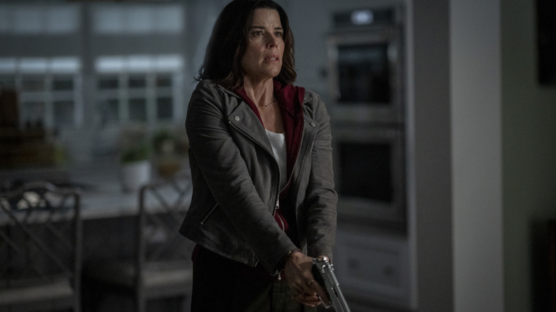 Neve Campbell as Sidney Prescott holding a gun inside a house in Scream 7