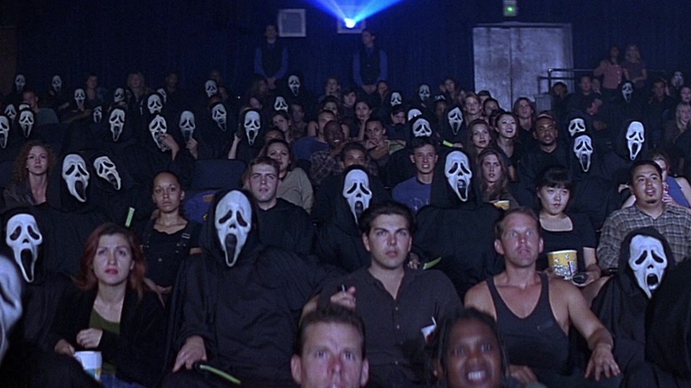 Een publiek van mensen, sommigen met spookmaskers in Scream 2