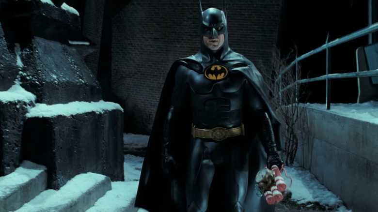 Michael Keaton's Batman walks through an alleyway holding a bomb in Batman Returns