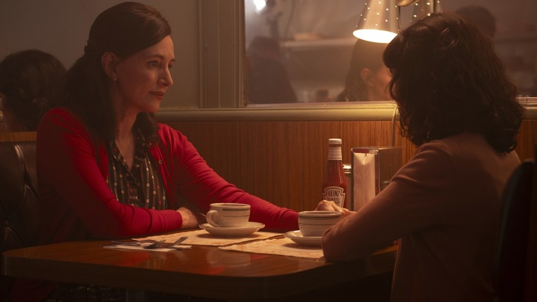 Madeline Stowe as Ingrid seated at a diner table and holding the hand of Clara Stack as Lilly in It: Welcome to Derry