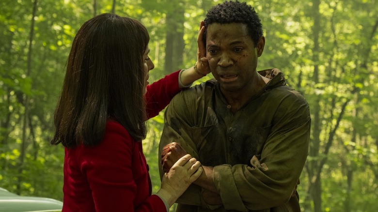 Madeline Stowe as Ingrid affectionately holding Stephen Rider as Hank Grogan in a forest in It: Welcome to Derry